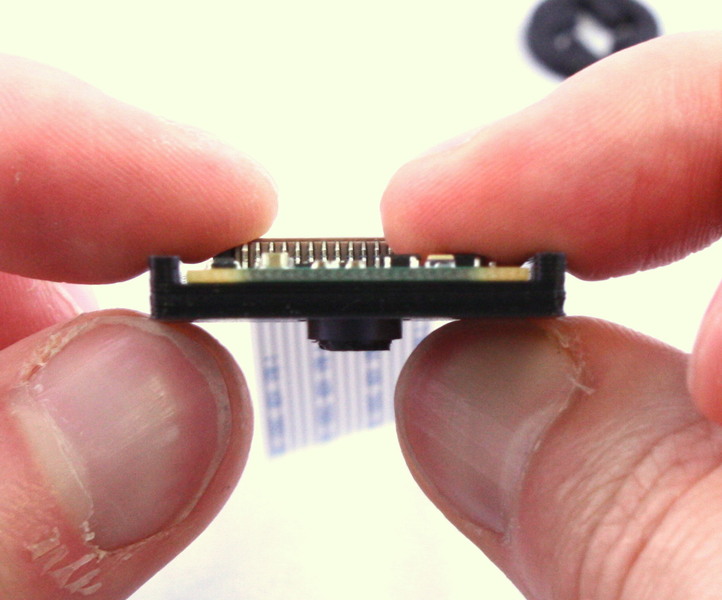 Gripping the camera to prevent damage to the ribbon cable